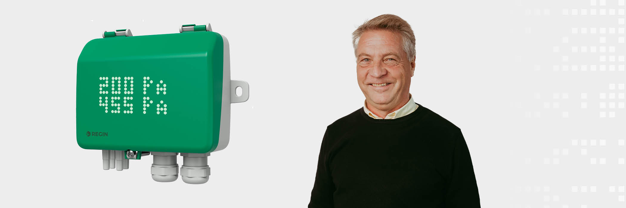 Green REGIN control box showing 200 Pa and 15.5 Pa, next to a man standing against a white background.